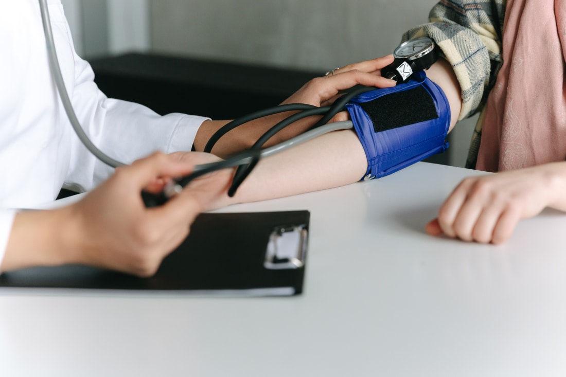 GP measures blood pressure on patient