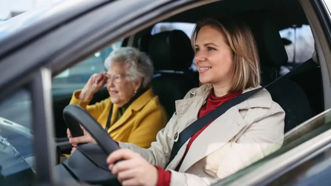 Woman is driving with an elderly lady in the car